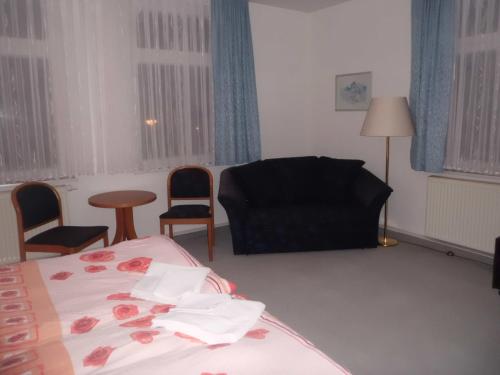 a bedroom with a bed and chairs and a couch at Pension "Parkhotel" Blankenhain in Blankenhain