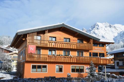 a large building with a balcony in the mountains at Pension Niederreiter in Maria Alm am Steinernen Meer