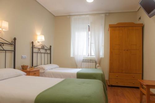 a bedroom with two beds and a cabinet and a window at Casa Rural Lagun Etxea in Pobes
