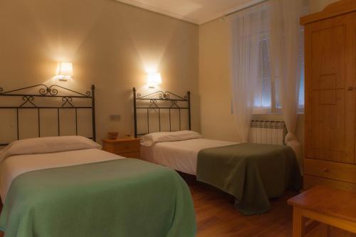 a bedroom with two beds with green and white sheets at Casa Rural Lagun Etxea in Pobes