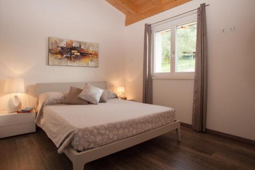 Un dormitorio blanco con una cama y una ventana. en Appartamento Campiano, en Malcesine