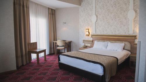Salihliにあるリディア サルデス ホテル サーマル ＆ スパのベッドとテーブルが備わるホテルルームです。