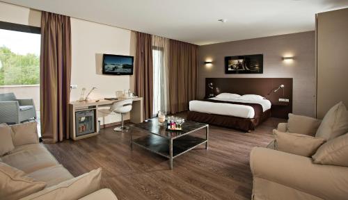 ル・カステレにあるGrand Prix Hôtel & Restaurantのベッドとリビングルームが備わるホテルルームです。