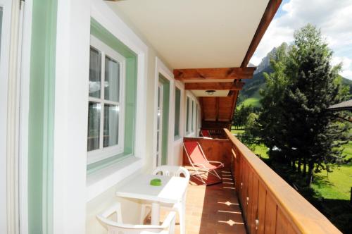a balcony with a white table and chairs on it at Casa El Tobià in Pozza di Fassa