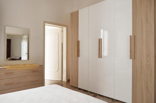 - une chambre avec des placards blancs et un miroir dans l'établissement Casa Mia, à Taurisano
