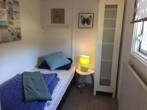 ein kleines Schlafzimmer mit einem Bett und einer Lampe auf einem Tisch in der Unterkunft Hygge House Nr. 413 in Andijk
