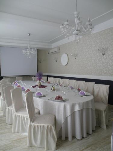 a conference room with a long table and white chairs at Hotel Bulevard Prestige in Slatina