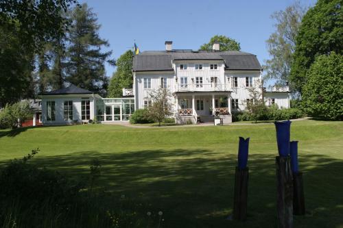 a large white house on a green lawn at Brunnbäcks Herrgård in Mästerbo