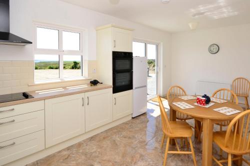 a kitchen with white cabinets and a table and a dining room at Cottage 311 - Clifden in Clifden