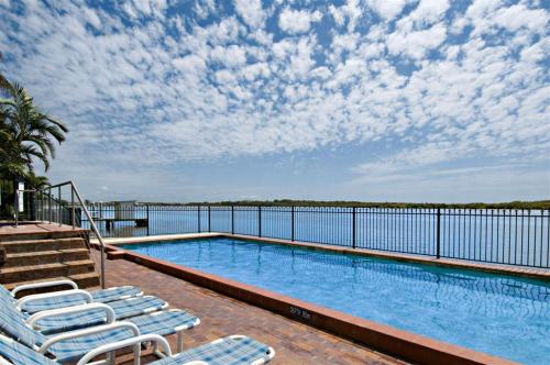 a swimming pool with lounge chairs and a view of the water at Banyandah Towers in Maroochydore