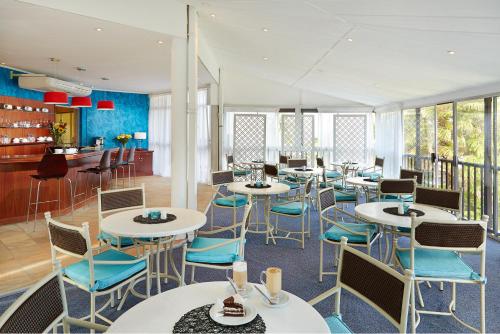 a restaurant with white tables and blue chairs at First Group La Cote D'Azur in Margate