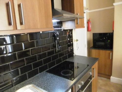 a kitchen with black tiled walls and a black counter top at Dewsbury House in Blackpool