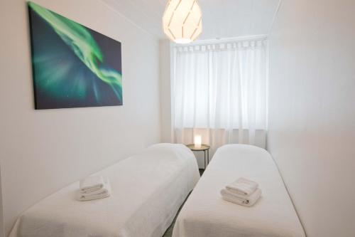 two beds in a white room with a window at Arctic Suite in Rovaniemi