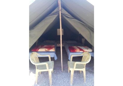 Shivpuri的住宿－Ubud Riverside Camps，帐篷配有2把椅子和2张床
