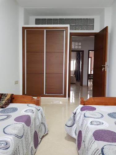 a bedroom with two beds and a door to a room at Appartement au Centre de Martil in Martil