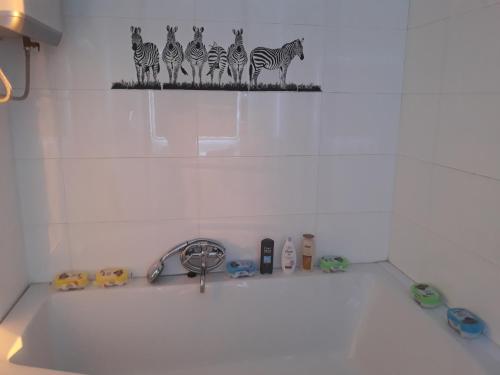 a bathroom sink with a faucet with zebras on the wall at Apartman BubaMara in Sveti Juraj