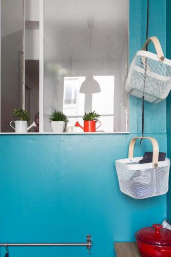 La salle de bains est pourvue d'un mur bleu et d'un miroir. dans l'établissement Veeve - Cosy Gambetta, à Paris