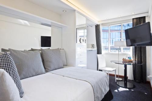 a white bedroom with a bed and a table and a tv at Meliá White House Hotel Apartments in London