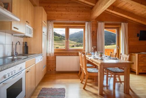 eine Küche mit einem Tisch mit Stühlen und einem großen Fenster in der Unterkunft Haus Panoramablick in Kals am Großglockner