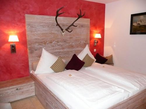 a bedroom with a white bed with antlers on the wall at Romantik Hotel Chalet am Kiental in Herrsching am Ammersee