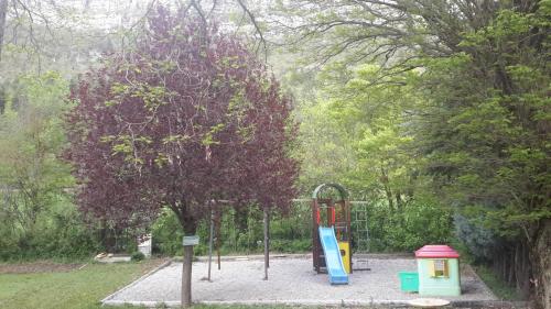 a playground in a park with a tree at Camping du lac in Saint-Julien-du-Verdon