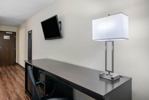 a desk with a lamp and a tv on a wall at Econo Lodge Inn & Suites Springfield Main Street in Springfield