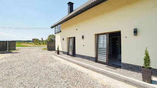 a white house with a door and a gravel driveway at Apartament Perła Pienin in Dębno