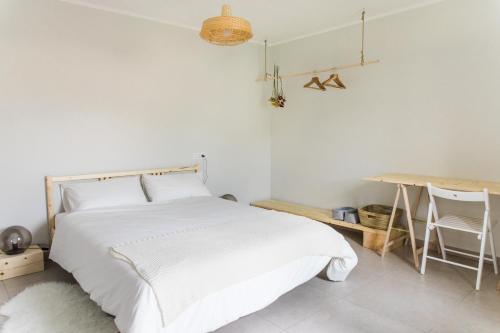 a white bedroom with a bed and a desk at Hiša Bubi in Tolmin