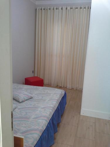 a bedroom with a bed and a window with curtains at Sobrado na Cidade de Socorro in Socorro