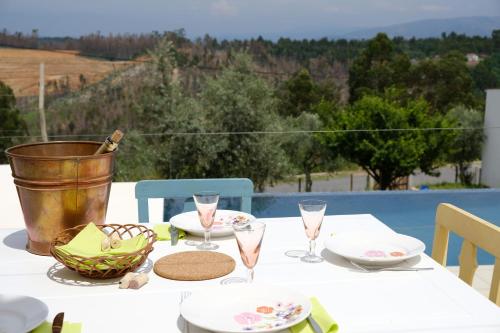 a white table with glasses and a basket on it at Vale Coelhos Casa de Campo in Sarnadela