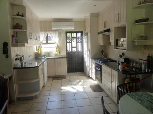 a kitchen with white cabinets and a tile floor at Sole's Leap in Scottburgh