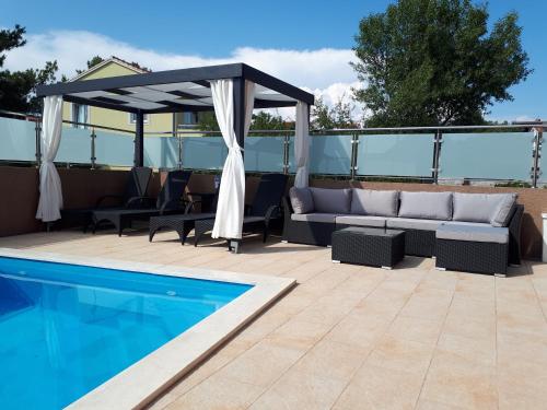 une terrasse avec un canapé et un auvent à côté d'une piscine dans l'établissement Apartments Melon Vodice, à Vodice