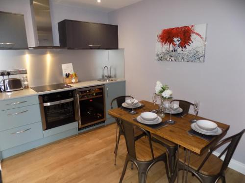 uma cozinha com uma mesa de madeira com cadeiras e uma sala de jantar em The Old Wool House Apartments em Carlisle