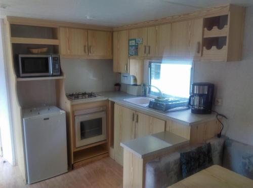a small kitchen with wooden cabinets and a white refrigerator at Camping du lac in Saint-Julien-du-Verdon