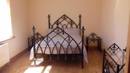 1 dormitorio con 1 cama de hierro en una habitación en Teach Nellie Cottage en Loughanure