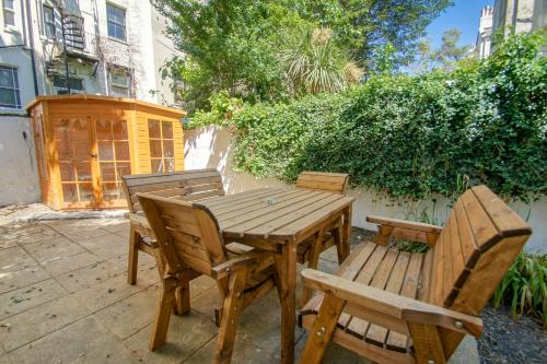 een houten tafel en stoelen op een patio bij Brunswick Garden Studio - Patio - by Brighton Holiday Lets in Brighton & Hove