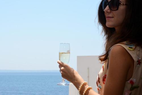 a woman holding a glass of wine next to a body of water at I Bastioni San Domenico in Gallipoli