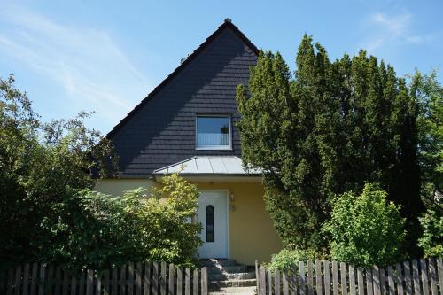una casa amarilla con techo negro y valla en Ferienwohnung Kochel mit Wallbox, en Gifhorn