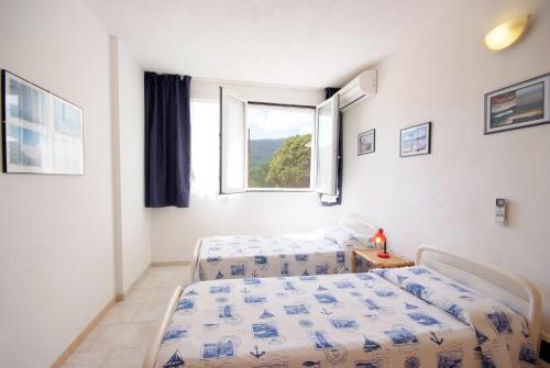 a bedroom with two beds and a window at Appartamenti Serenity - 2 posti auto - in villa e in centro in Marina di Campo