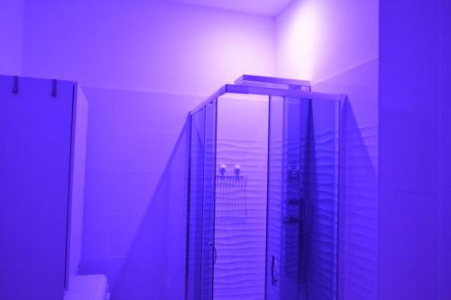 a bathroom with a glass shower with a purple light at Flamingo SPA Loft by Picasa Sicilia - SEASIDE - SEA & ORTIGIA VIEW in Siracusa