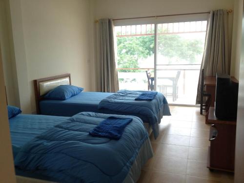 a hotel room with three beds and a balcony at Day Waterfront Hotel in Chiang Khong