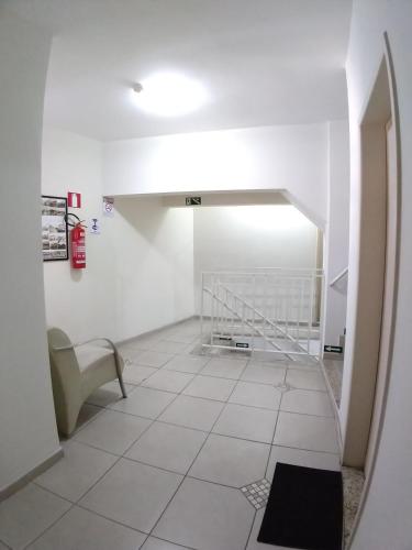 a hallway with a white tile floor and a staircase at Hotel Monte Carlo in São João del Rei