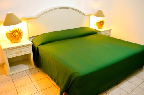 a bedroom with a green bed with two night stands at Hotel Costa Brava in Manzanillo