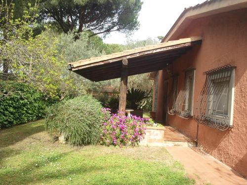 a porch of a house with a bunch of flowers at villetta nel verde vicino spiaggia in Orbetello