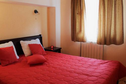a bedroom with a red bed with pillows and a window at Apartment Stanisic in Budva