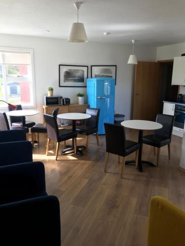 a living room with tables and chairs and a kitchen at Framtid Hostel in Djúpivogur