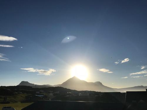 a view of a mountain with the sun in the sky at Framtid Camping Lodging Barrels in Djúpivogur