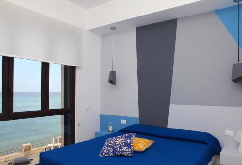 a bedroom with a blue bed with a view of the ocean at Sea Windows Suite in Trapani