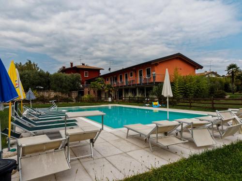 a swimming pool with chairs and umbrellas next to a building at Agriturismo Al Dugale in Lazise