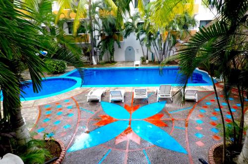 a resort pool with a blue pool with palm trees at Hotel Costa Brava in Manzanillo